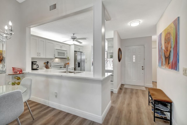 kitchen featuring kitchen peninsula, sink, white cabinetry, light hardwood / wood-style flooring, and white appliances