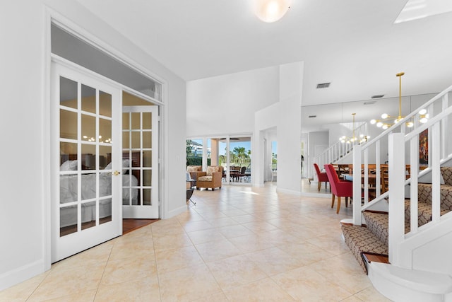 tiled entrance foyer with french doors, a high ceiling, and an inviting chandelier