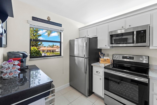 kitchen with appliances with stainless steel finishes, light tile patterned floors, and white cabinets