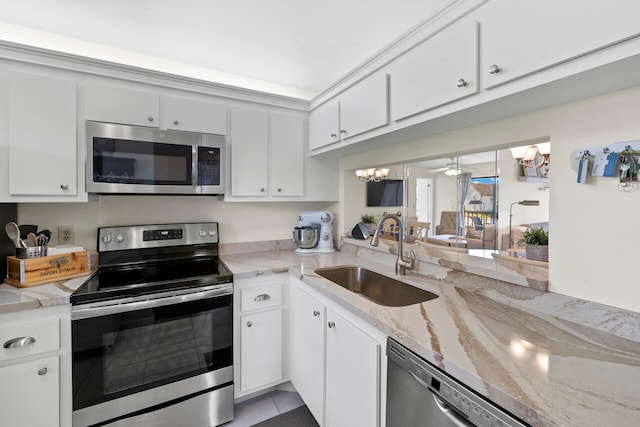 kitchen with light stone counters, sink, stainless steel appliances, and white cabinets