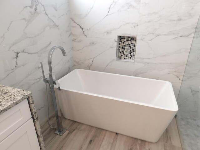 bathroom with tile patterned floors, tiled tub, and vanity