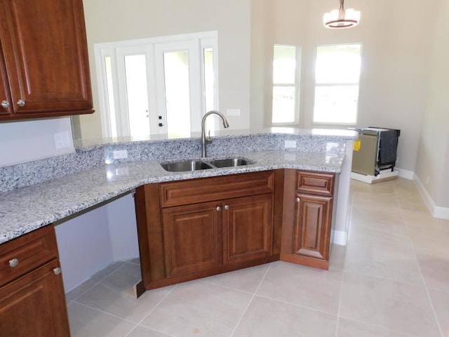 kitchen with light stone countertops, kitchen peninsula, light tile patterned flooring, and sink