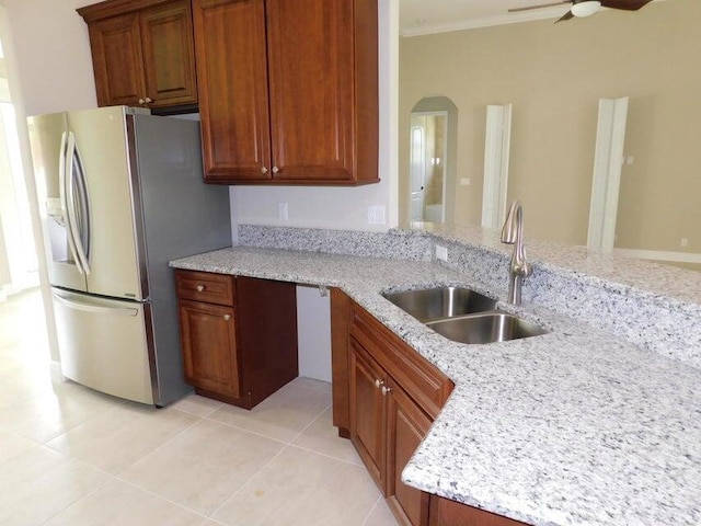 kitchen featuring sink, ceiling fan, stainless steel fridge, light tile patterned floors, and light stone counters