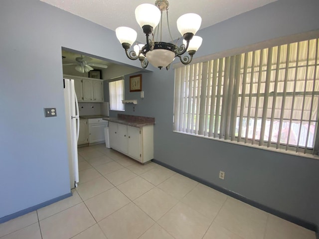 kitchen with ceiling fan with notable chandelier, plenty of natural light, light tile patterned floors, and white refrigerator