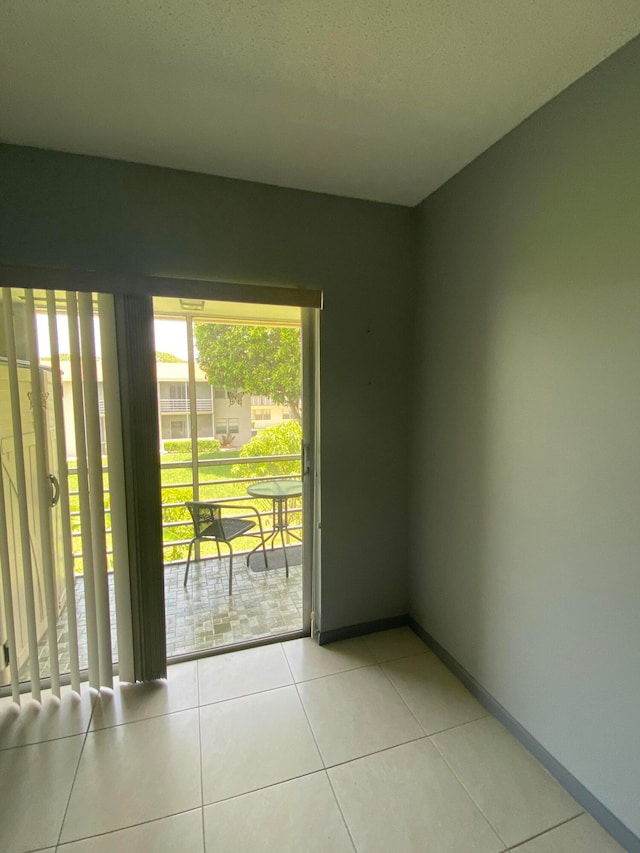 doorway to outside with a textured ceiling and light tile patterned floors