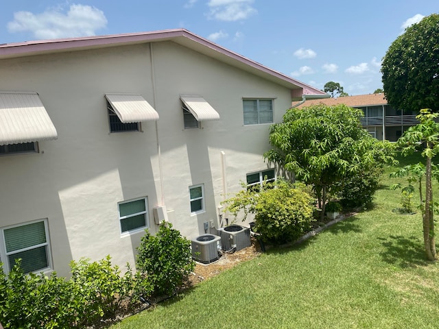 back of property featuring central AC unit and a yard