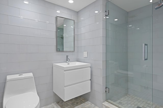 bathroom with toilet, vanity, tile walls, and a shower with door