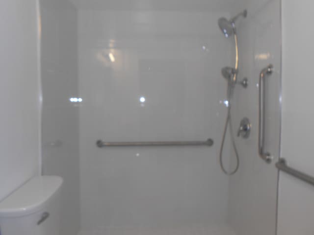 bathroom featuring walk in shower and toilet