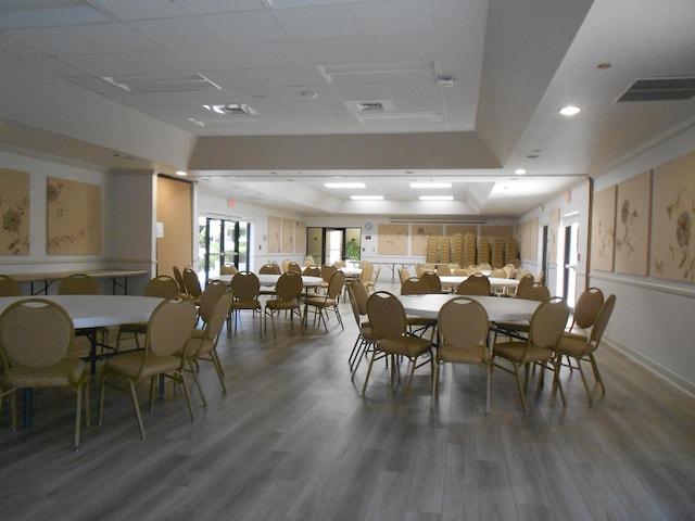 dining room with wood-type flooring, a tray ceiling, and a drop ceiling