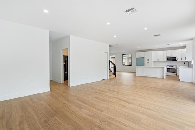 unfurnished living room with light hardwood / wood-style floors and sink