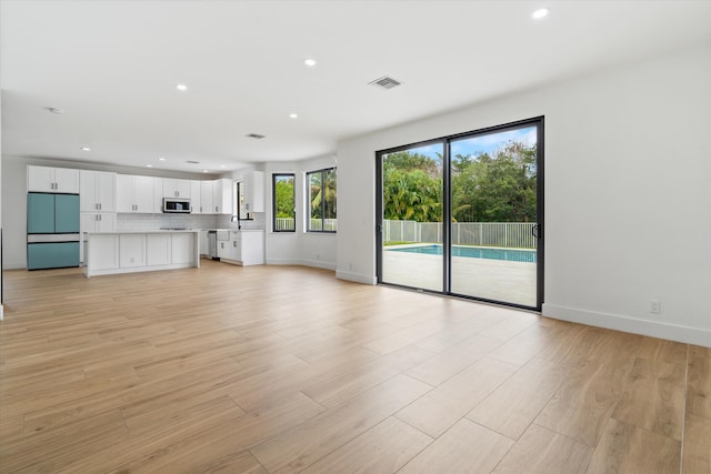 unfurnished living room featuring light wood-type flooring and sink