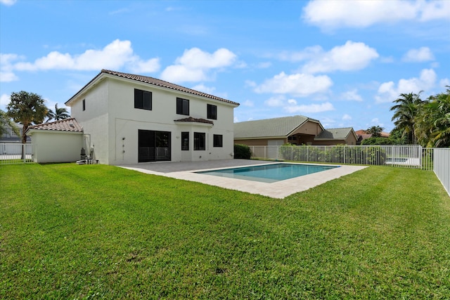 rear view of property with a fenced in pool, a patio area, and a yard