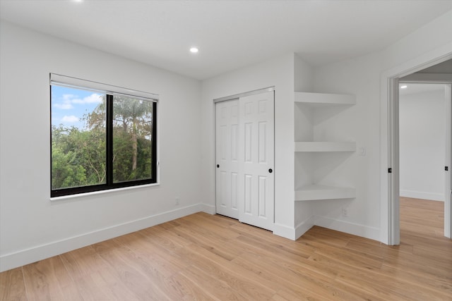 unfurnished bedroom with a closet and light wood-type flooring