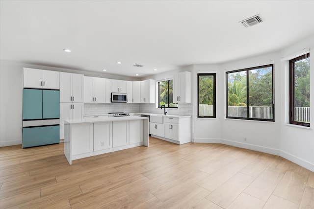 kitchen with stainless steel appliances, plenty of natural light, and white cabinets