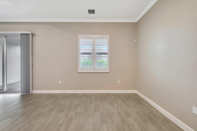 empty room featuring light wood-type flooring and ornamental molding