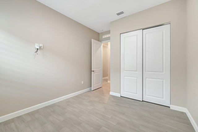 unfurnished bedroom featuring light hardwood / wood-style flooring and a closet