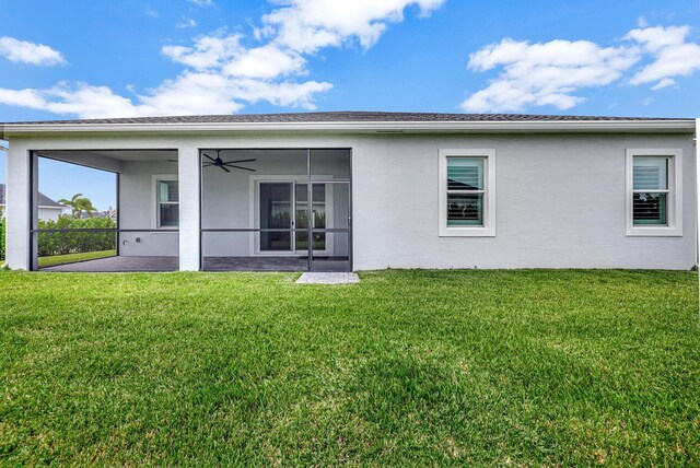 back of house with ceiling fan and a lawn