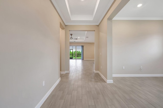 hallway with a raised ceiling, ornamental molding, and light hardwood / wood-style flooring