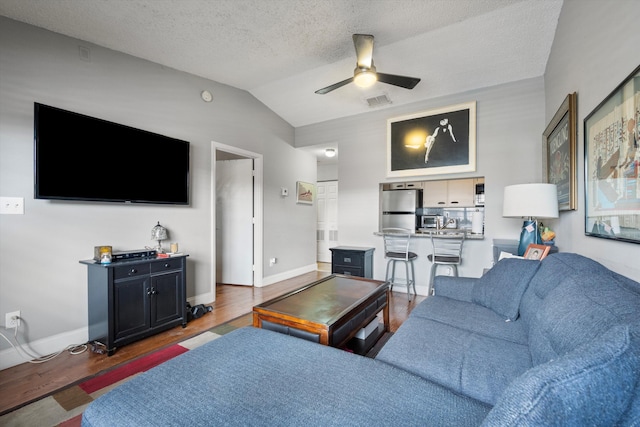 living room with dark hardwood / wood-style floors, ceiling fan, lofted ceiling, and a textured ceiling