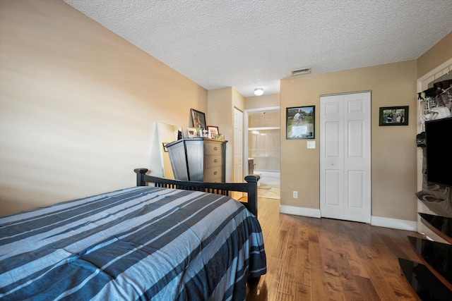 bedroom with a textured ceiling, connected bathroom, and dark hardwood / wood-style floors