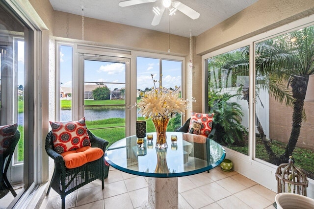 sunroom / solarium featuring a water view and ceiling fan