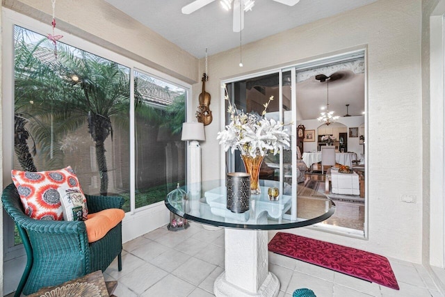 sunroom featuring ceiling fan with notable chandelier and a wealth of natural light