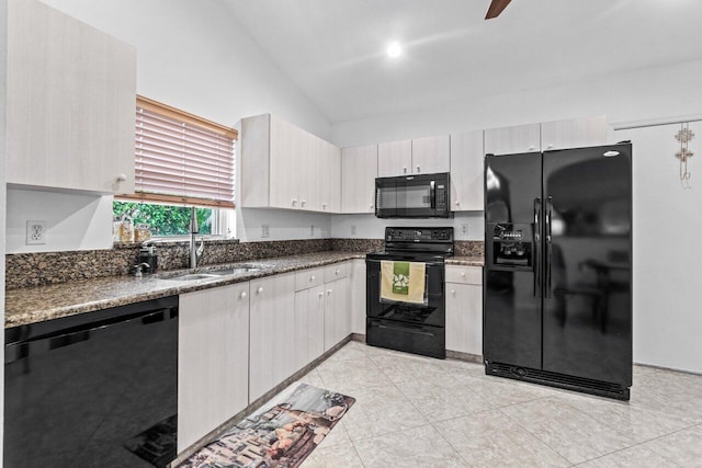 kitchen with dark stone countertops, sink, black appliances, and vaulted ceiling