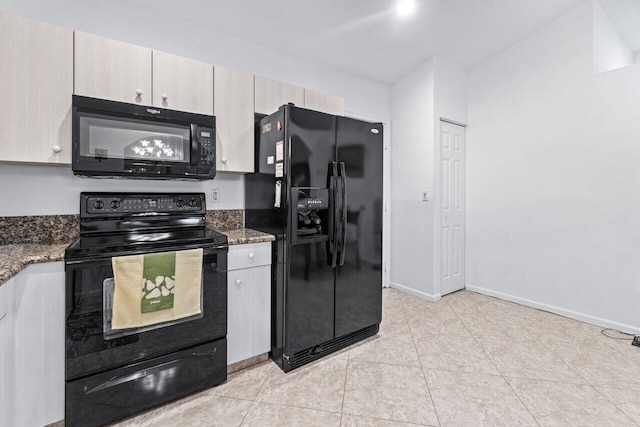 kitchen with dark stone counters, light tile patterned floors, and black appliances