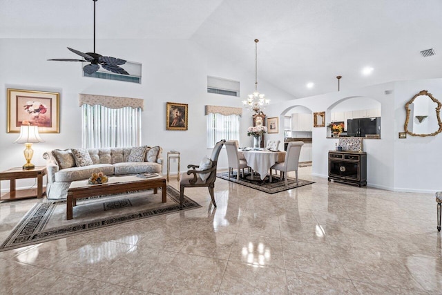 living room with ceiling fan with notable chandelier, plenty of natural light, and high vaulted ceiling