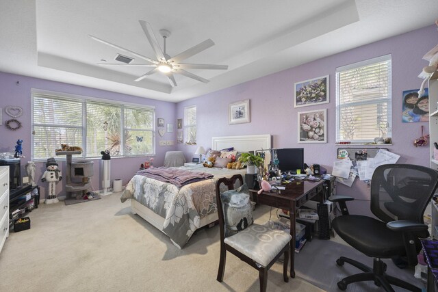 carpeted bedroom with ceiling fan and a tray ceiling