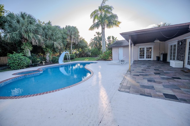 view of pool featuring french doors, a patio, a fenced in pool, and a water slide