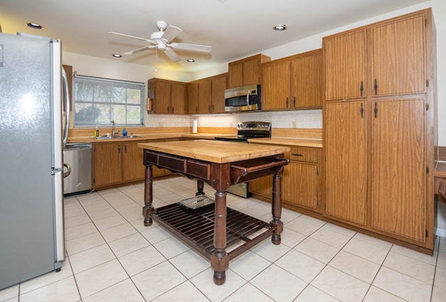 kitchen with decorative backsplash, appliances with stainless steel finishes, ceiling fan, sink, and light tile patterned floors