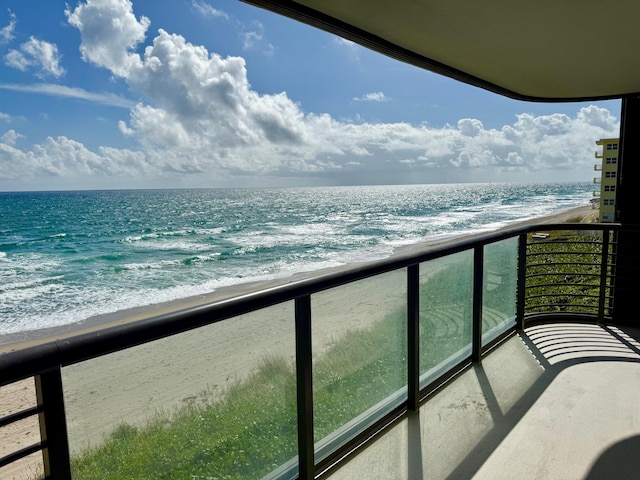 balcony with a water view and a view of the beach