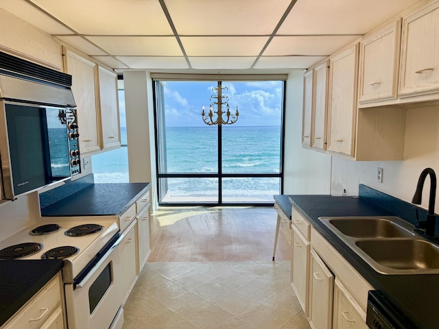 kitchen featuring pendant lighting, white electric range, sink, a chandelier, and a water view