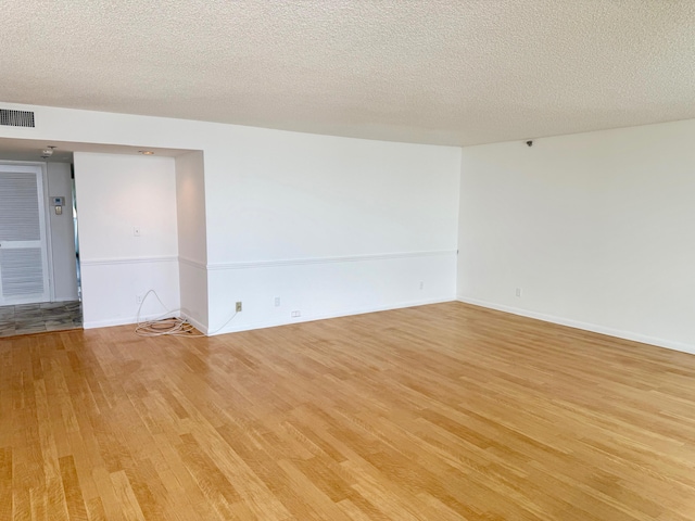 unfurnished room featuring light hardwood / wood-style floors and a textured ceiling