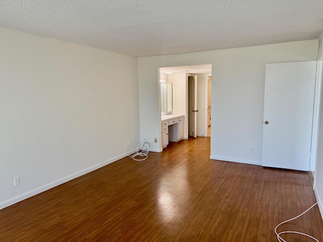 spare room with a textured ceiling and dark hardwood / wood-style floors