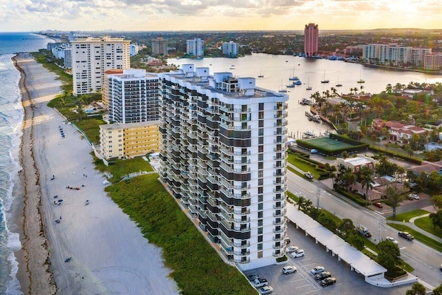 aerial view at dusk with a water view and a view of the beach