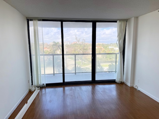 spare room featuring a wall of windows, dark wood-type flooring, and a wealth of natural light