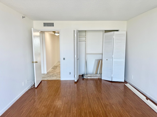 unfurnished bedroom featuring a textured ceiling, a closet, and hardwood / wood-style floors