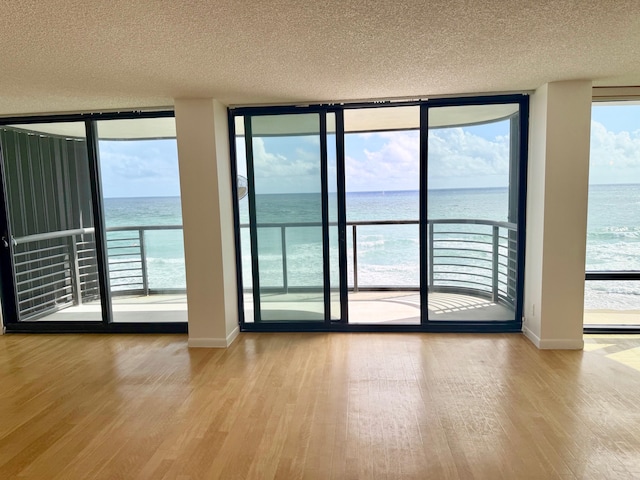 entryway featuring a textured ceiling, a water view, and light wood-type flooring