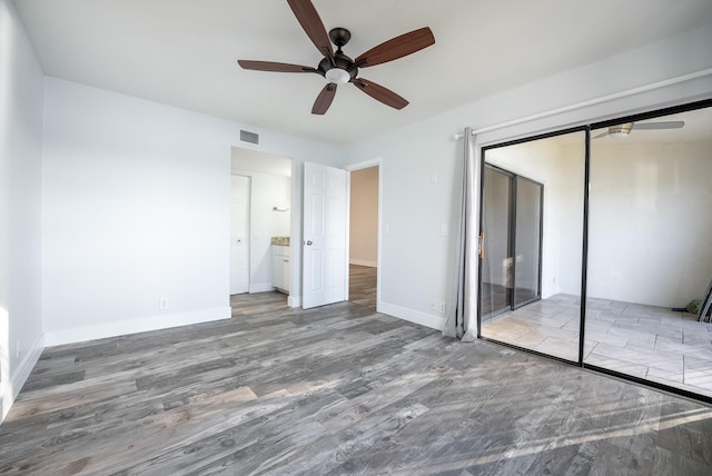 unfurnished bedroom featuring ceiling fan, ensuite bath, a closet, and hardwood / wood-style floors