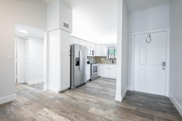 kitchen featuring tasteful backsplash, light hardwood / wood-style floors, sink, white cabinetry, and appliances with stainless steel finishes