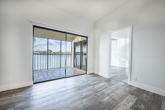 unfurnished room with hardwood / wood-style floors, a water view, and vaulted ceiling