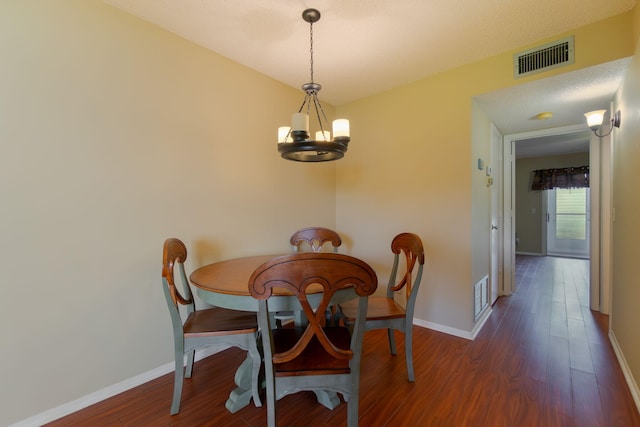 dining space with dark hardwood / wood-style floors and an inviting chandelier