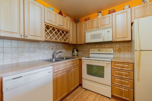 kitchen with tasteful backsplash, light wood-type flooring, white appliances, and sink