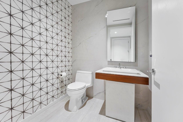 bathroom featuring sink, tile walls, and toilet