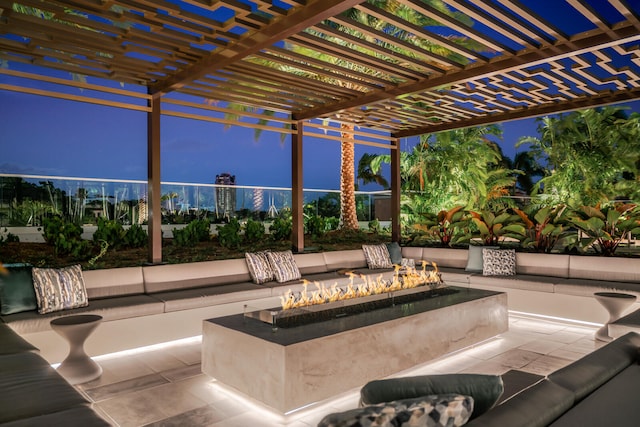 patio terrace at dusk featuring a pergola and an outdoor fire pit