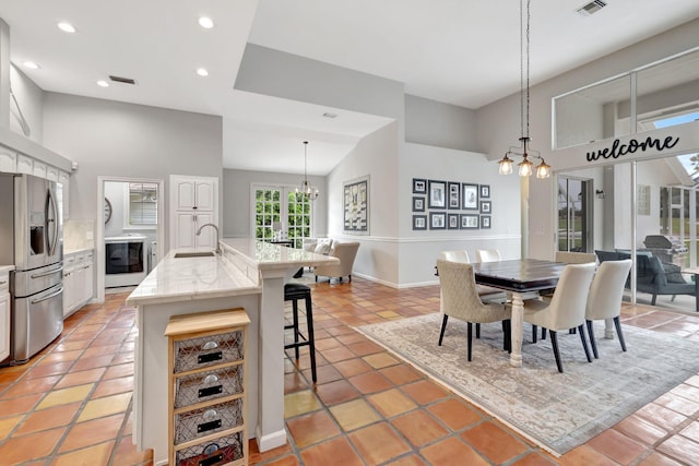 dining space with light tile patterned floors, high vaulted ceiling, an inviting chandelier, and sink