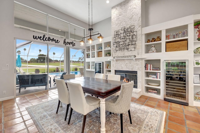 tiled dining room with wine cooler, built in features, a fireplace, and a high ceiling