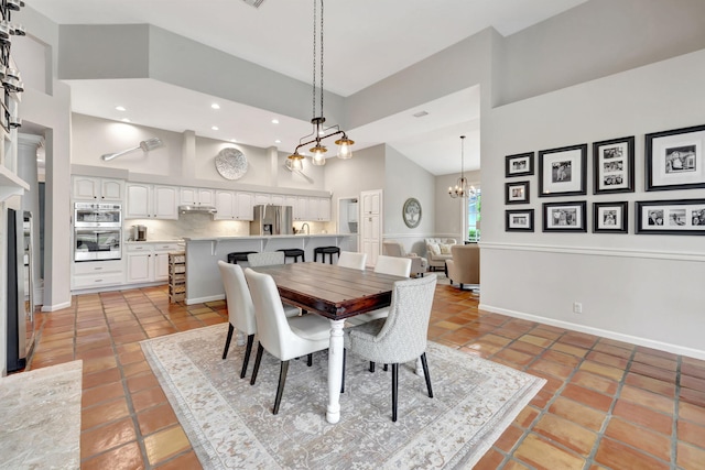 tiled dining area with a towering ceiling and a chandelier